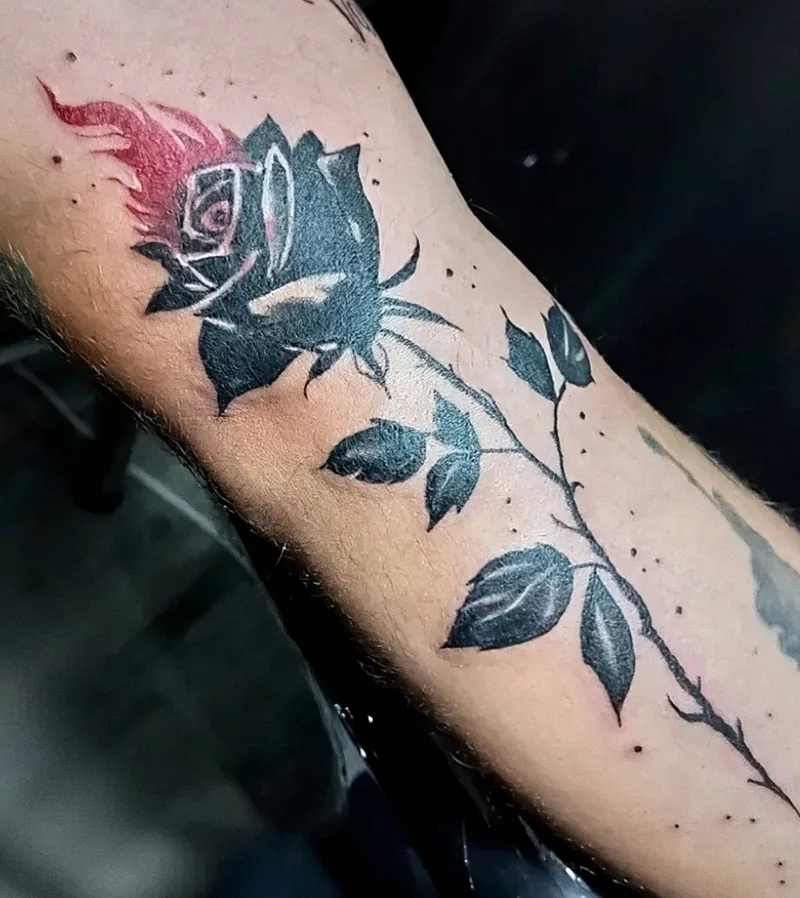 Rosa en color con hojas y tallo tatuada en el antebrazo