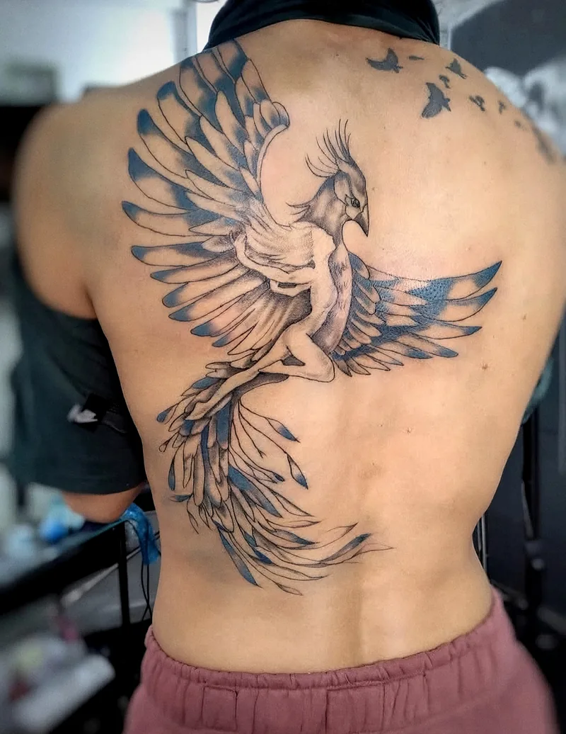 Fénix ilustrativo con alas desplegadas y sombras azules, tatuado en la espalda