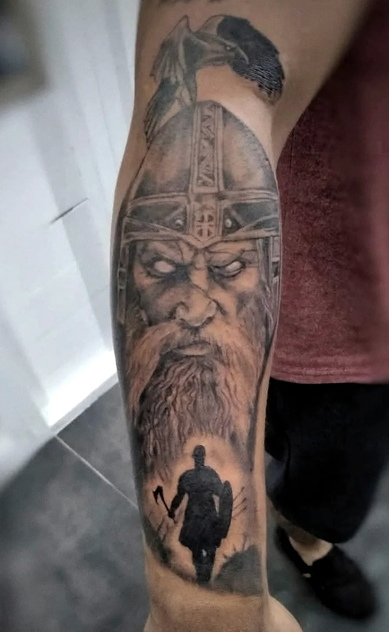 Guerrero vikingo con casco en realismo black & grey, tatuado en la pierna