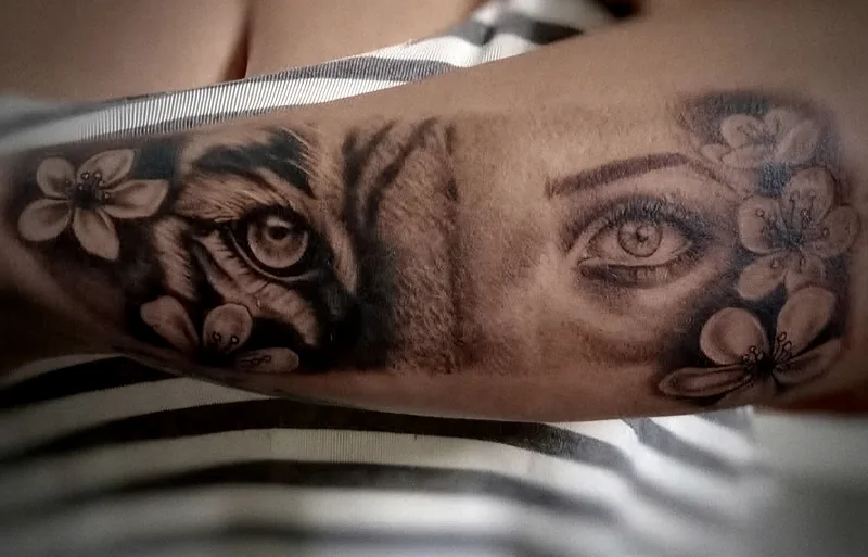Ojo de tigre y ojo de mujer entre flores de cerezo, tatuados en el antebrazo